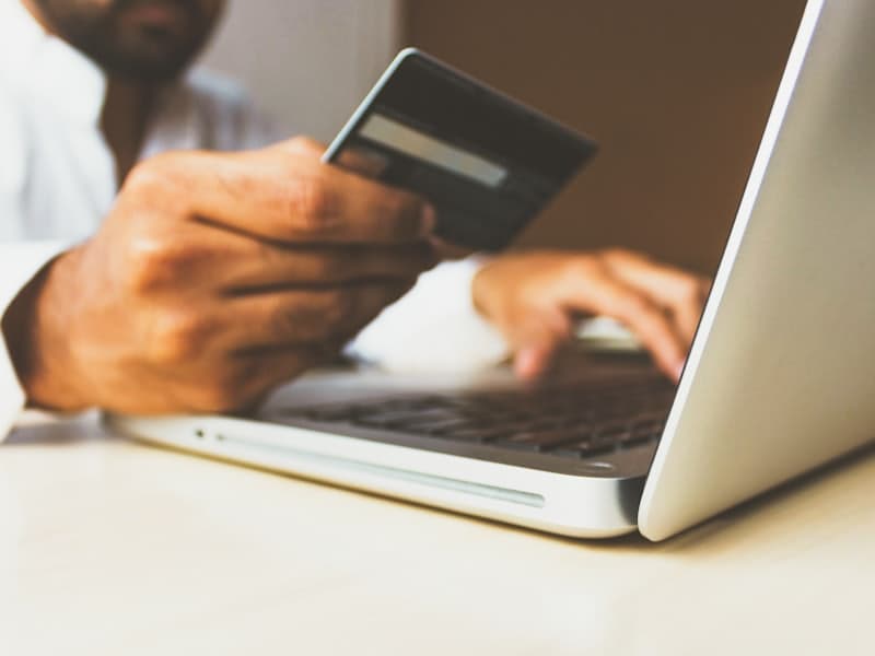 Pessoa comprando online com cartão de crédito em frente ao notebook